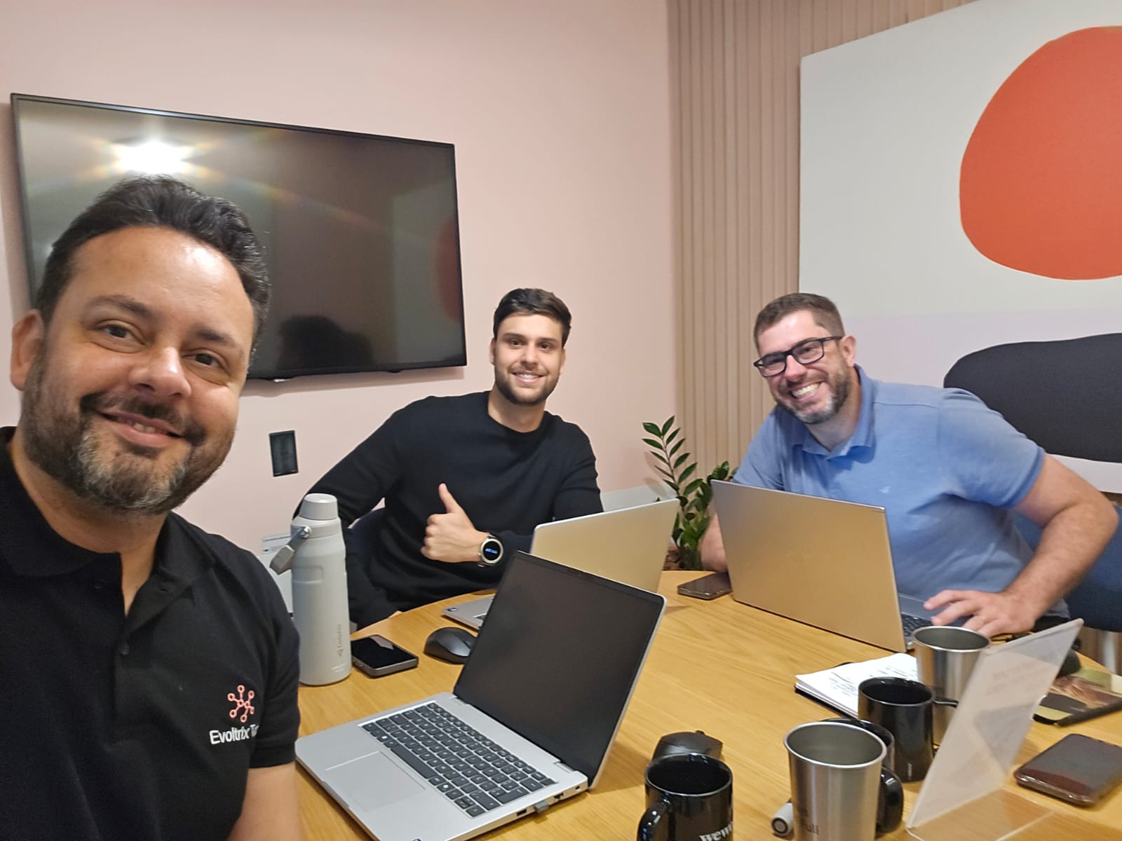 Líderes da Evoltrix Tech reunidos, com laptops sobre a mesa de trabalho